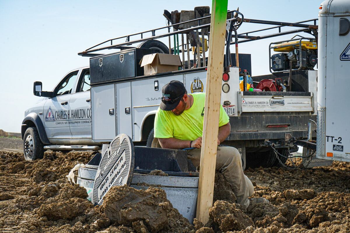  Man using construction equipment with truck in the background