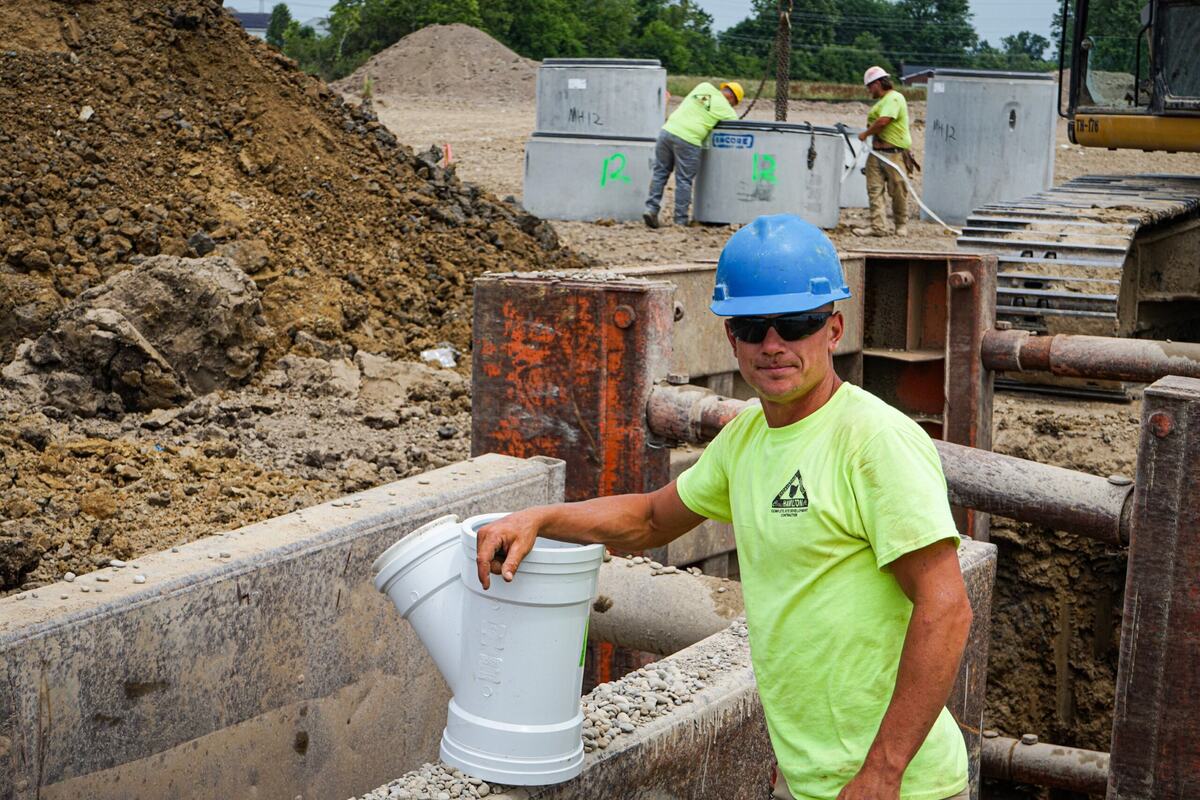 Man on construction site holding pipe