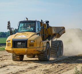 Large Cat dump truck driving down a construction site.