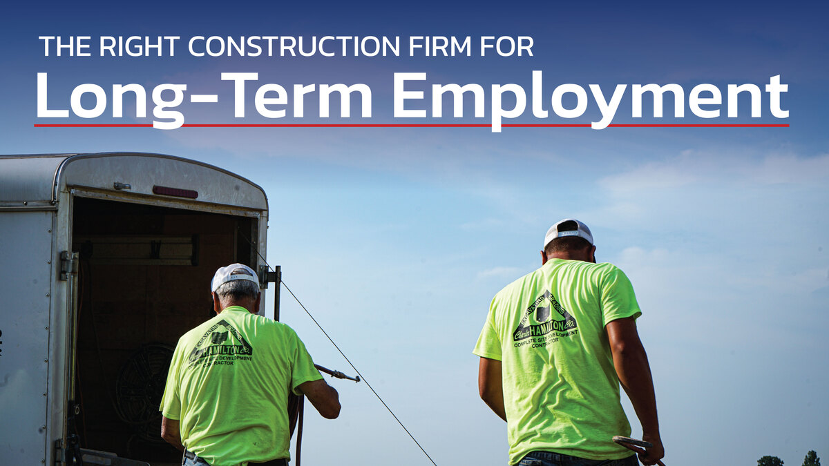 Two construction workers stand next to a trailer text reads the right construction firm for long term employment