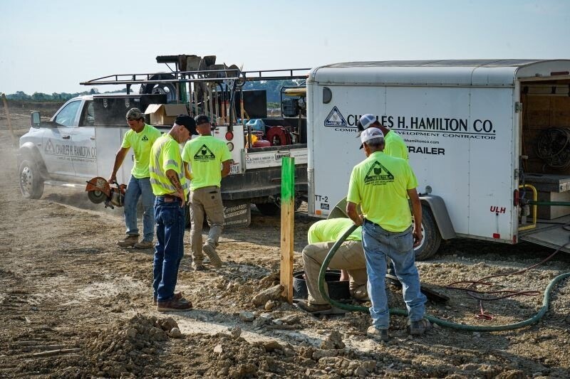 workers standing above a hole next to their trailer