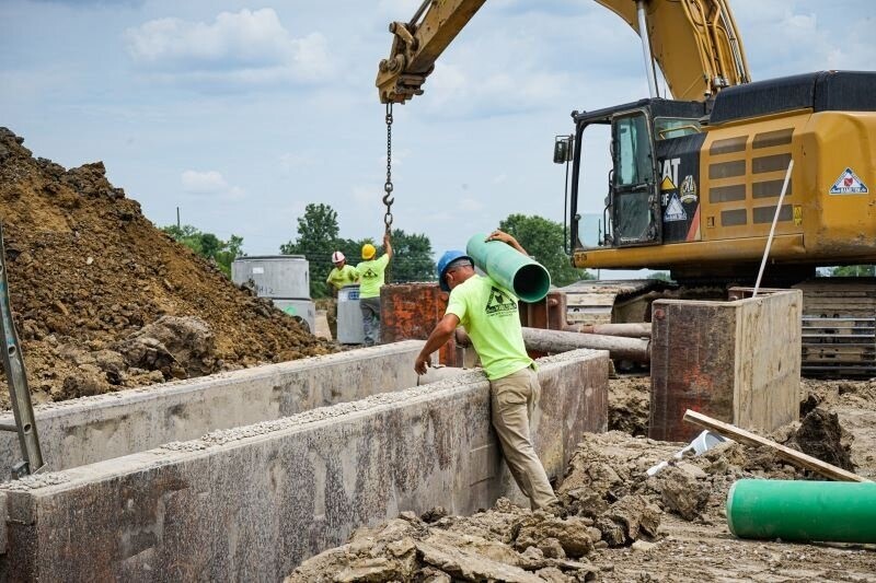 A worker carrying a large tube onto his shoulder