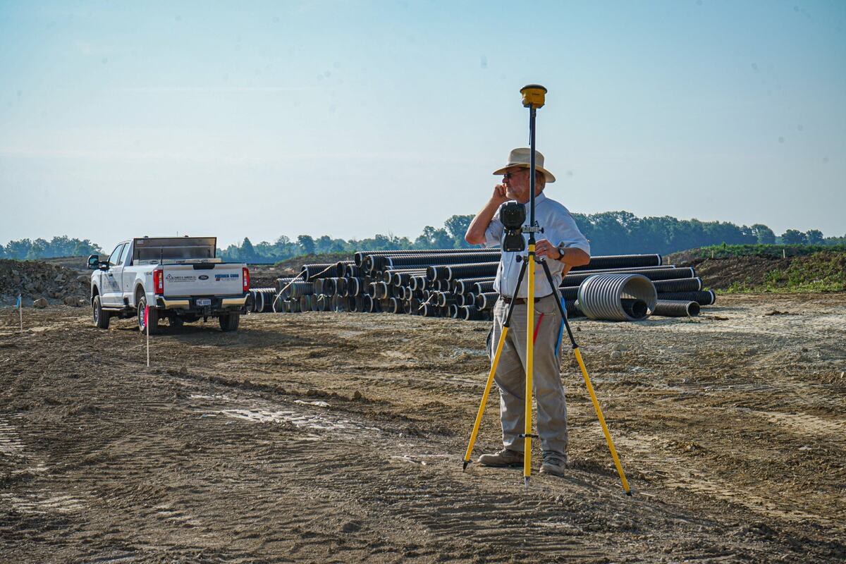 Man surveying landscape with construction equipment in the background